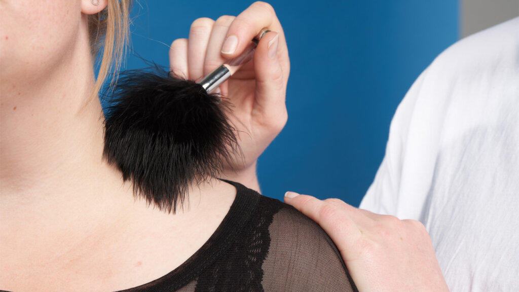 Une personne se fait chatouiller le cou avec une plume