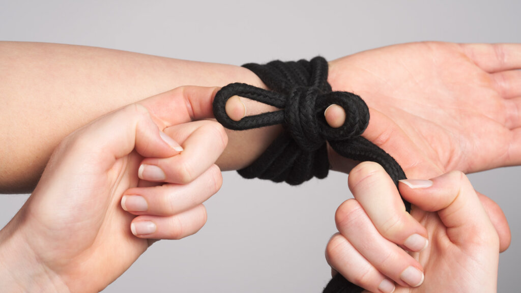 Hands tying a knot around a wrist 