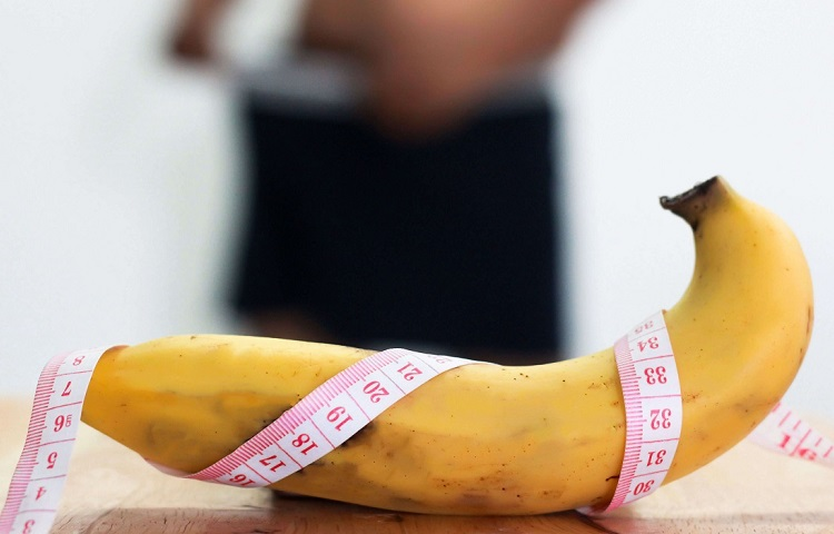Banana with measuring tape around lying on a wooden table