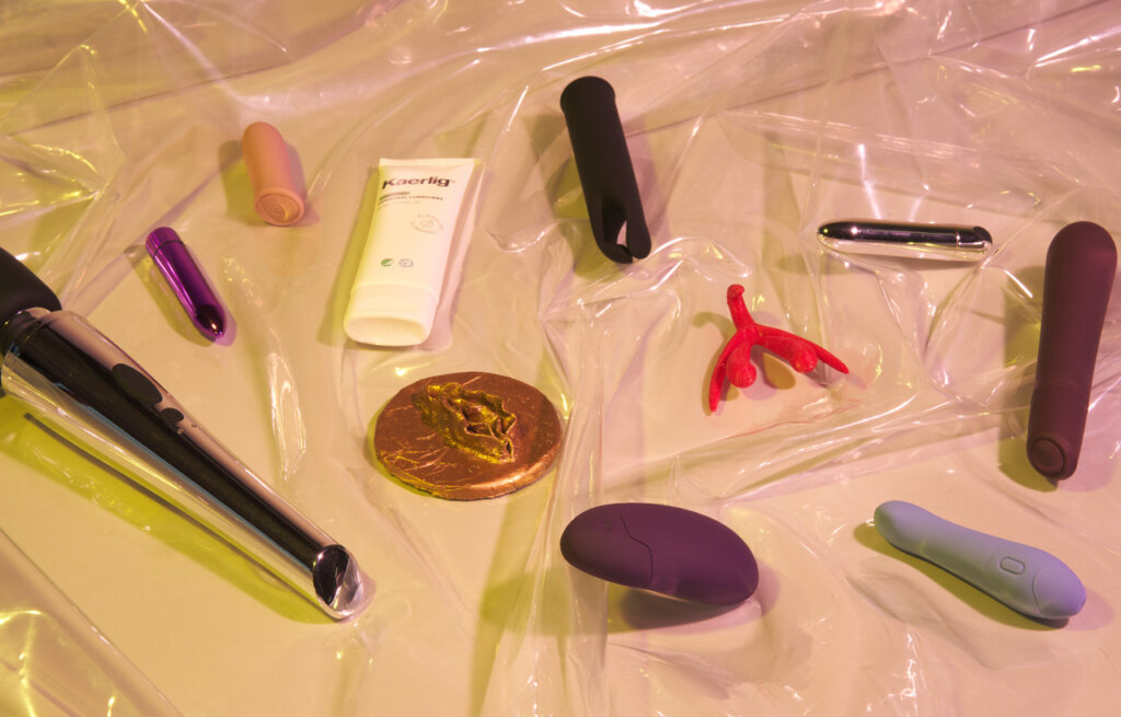Diverse produkter til klitoris ligger på gennemsigtigt plastik på en beige baggrund