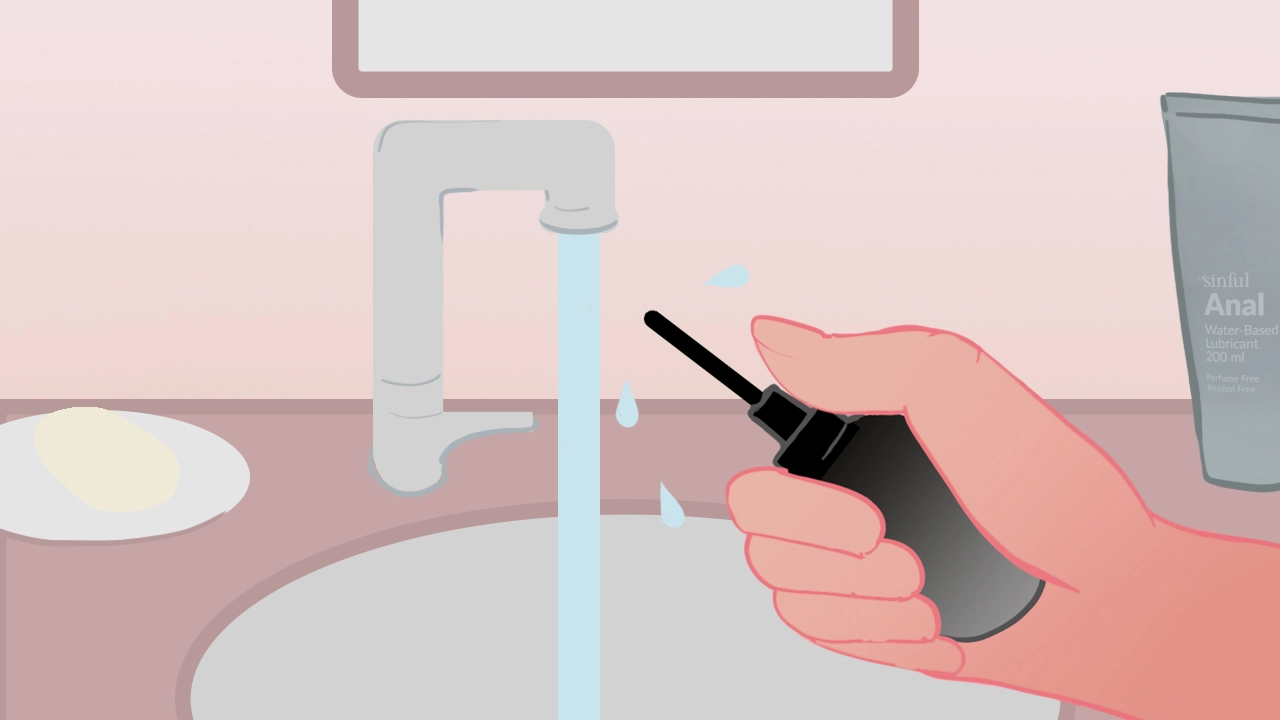 Illustration d'une main tenant une poire à lavement anal noire sous un robinet