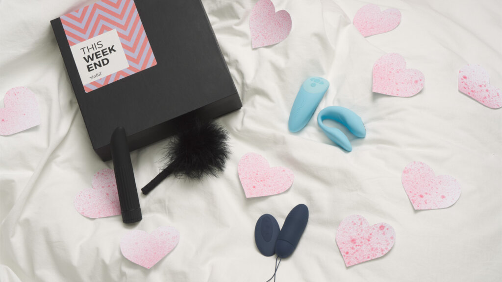 Three pieces of sex toys and big pink hearts lie next to each other