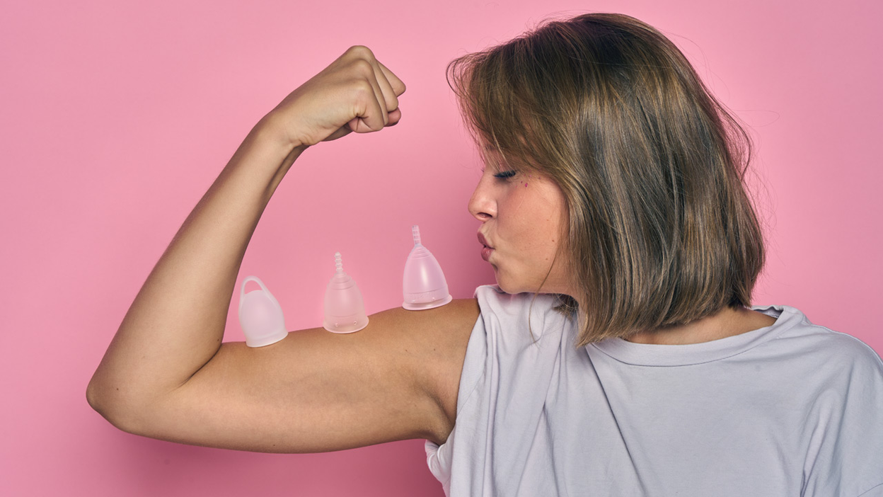 Une femme pliant le bras avec trois coupes menstruelles sur le biceps