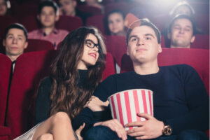 Ungt par der sidder i biografen med popcorn