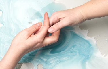 Twee handen houden boven een blauwe vloeistof