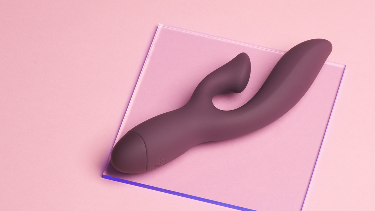 Purple rabbit vibrator lying on a glass plate on a pink background