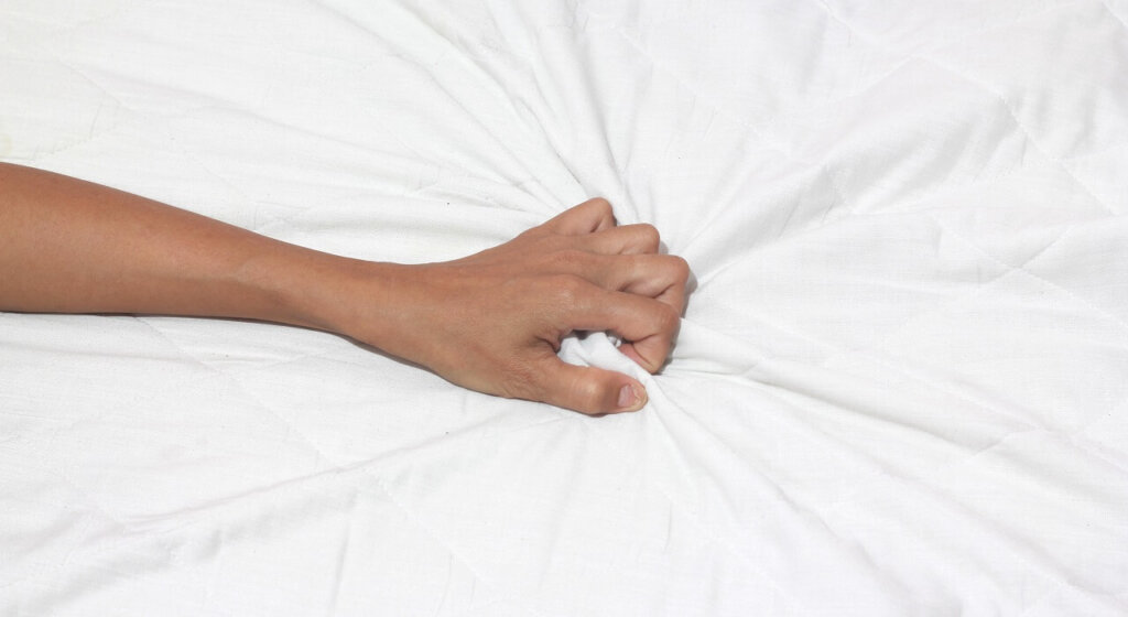 Hand grabbing hold of bed sheets
