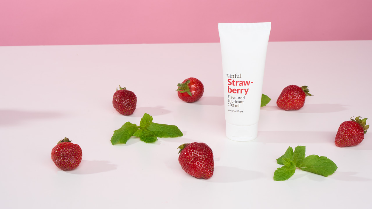 Flavoured lube on a table along with six strawberries