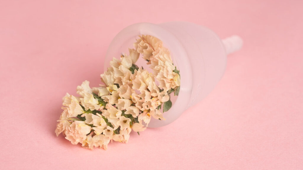 Menstruationstasse mit Blumen im Inneren