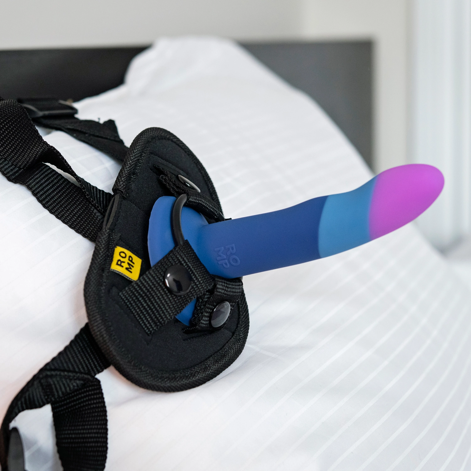 A pegging dildo in a harness lying on a pillow