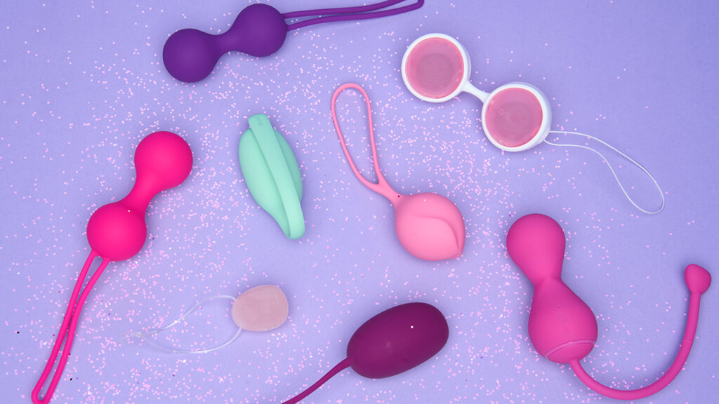 Lots of kegel balls in different colours on a light purple background with glitter