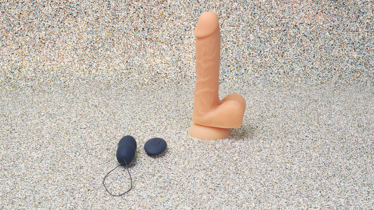 Realistic dildo in beige and blue vibrator egg with remote control on glitter background