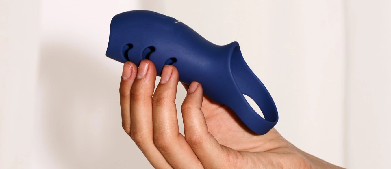 Een hand die een blauwe siliconen penismanchet vasthoudt.