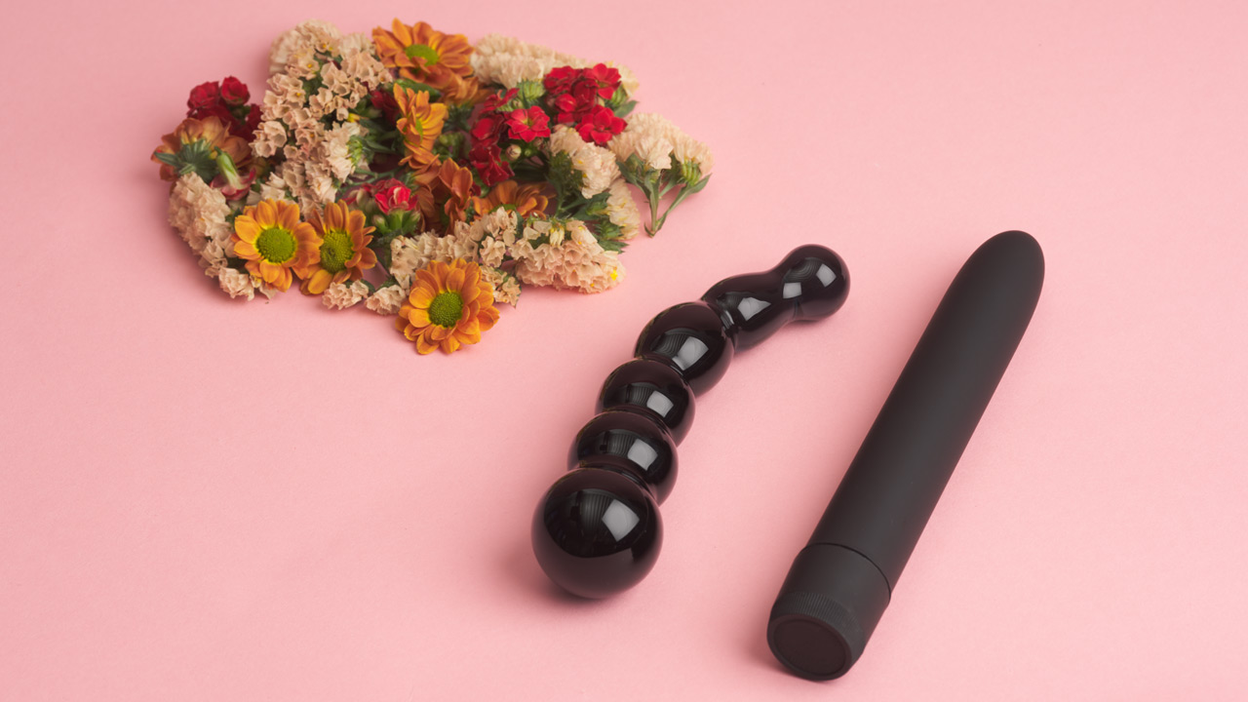 Sex toys and flowers on a pink background