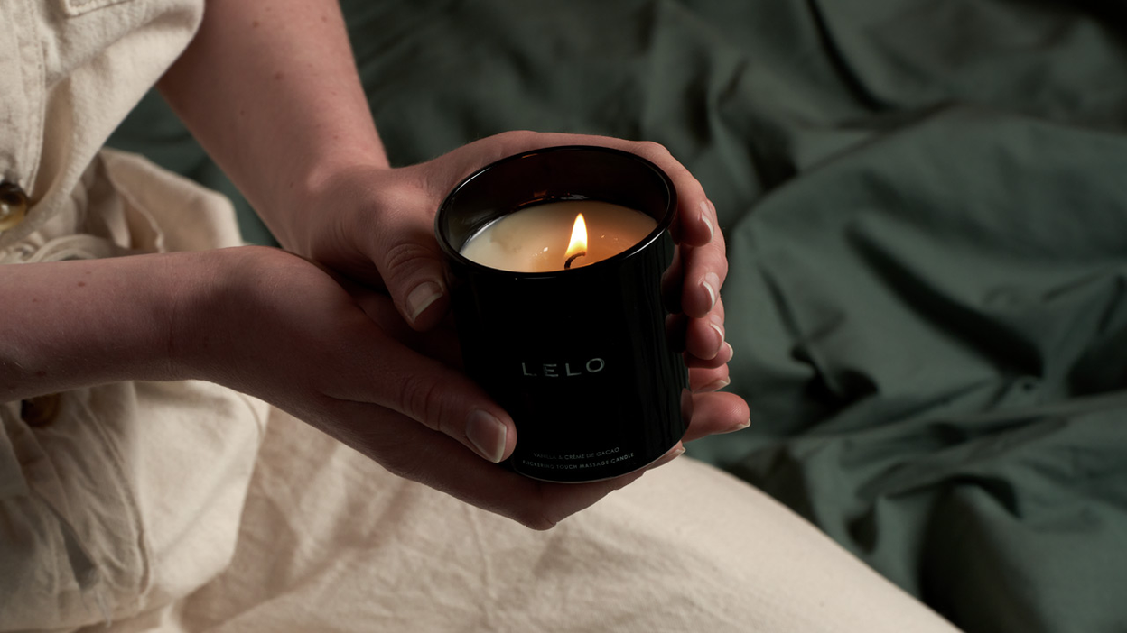 hands holding a lit Lelo massage candle