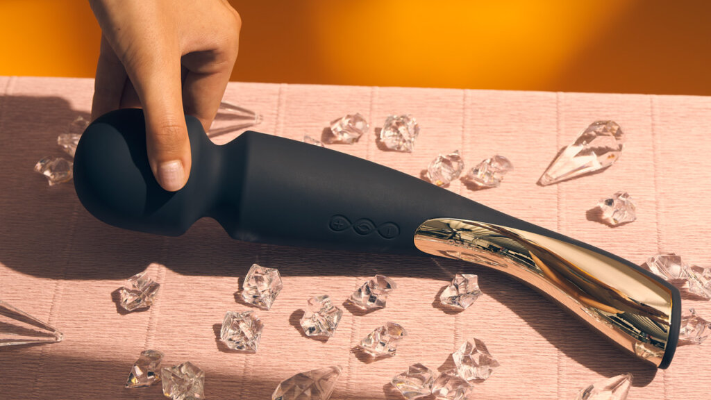 Black piece of sex toy lies on a table with crystals