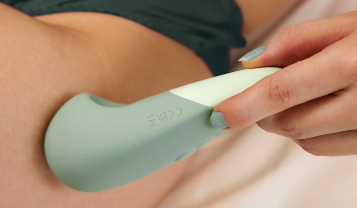Une femme fait glisser un Womanizer Vibe contre sa peau.