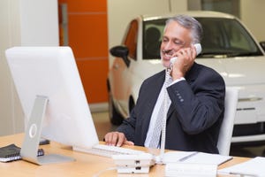 Dealer - on phone at car dealership