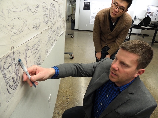 Instructor Brian Stoeckel foreground discusses early design sketches with CCS student Fred Zehao Liu