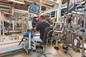 Worker installs gasket on back of engine at VW plant