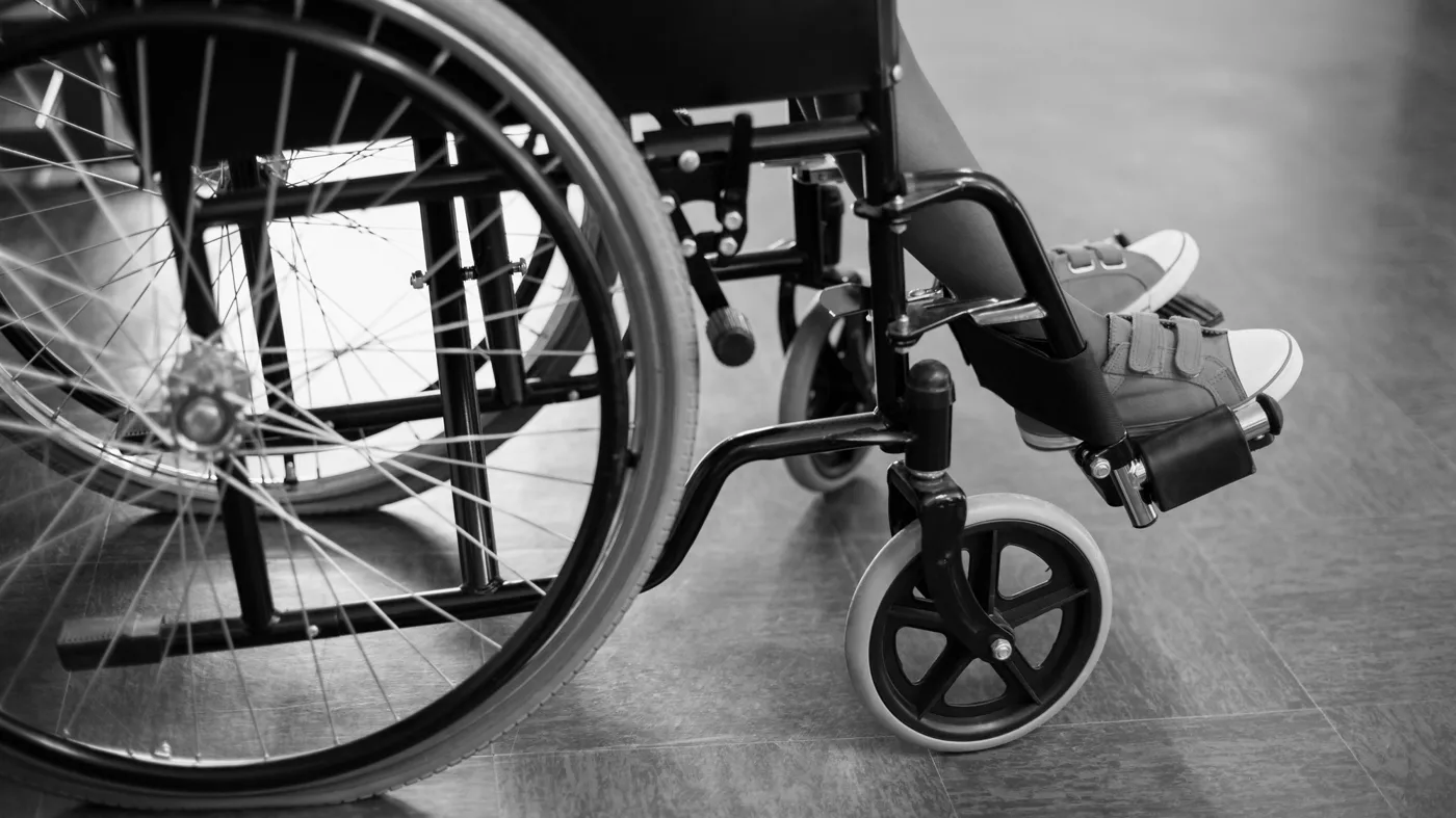 Black and white photo of a child in a wheelchair, close-up so only legs are visible Black and white photo of a child in a wheelchair, close-up so only legs are visible