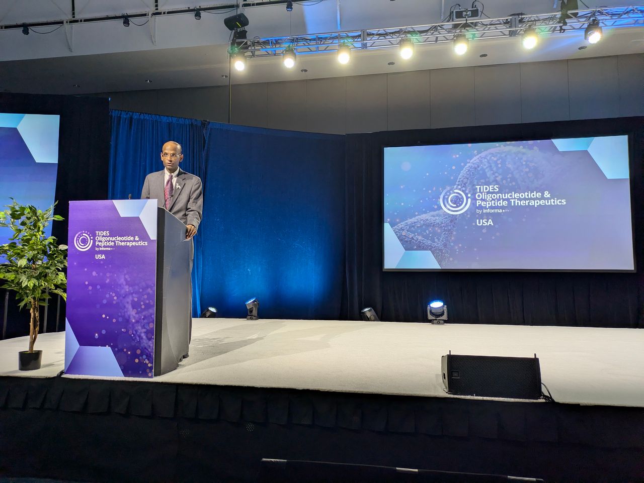 Photo of Kiran Musunuru delivering a keynote talk at TIDES USA on stage