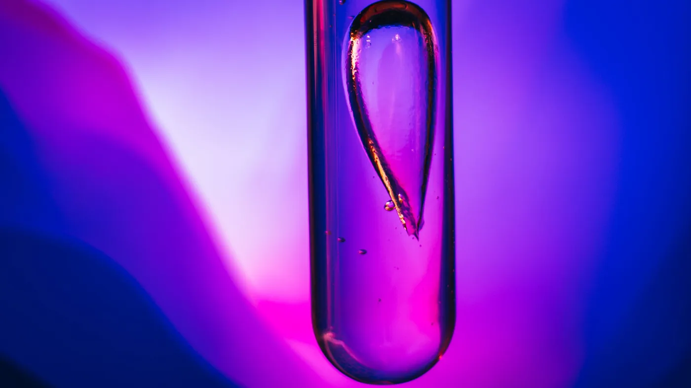 Photo of a vial with an upside-down droplet inside of it, whole image is washed in deep and vibrant pink/purple hues Photo of a vial with an upside-down droplet inside of it, whole image is washed in deep and vibrant pink/purple hues
