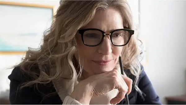 Μια γυναίκα με γυαλιά κράταει ένα στυλό και διαβάζει
