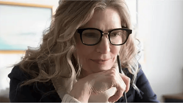 Μια γυναίκα με γυαλιά κράταει ένα στυλό και διαβάζει