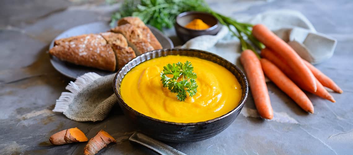 A bowl of creamy cauliflower turmeric soup with a vibrant yellow color, garnished with a sprig of fresh parsley A bowl of creamy cauliflower turmeric soup with a vibrant yellow color, garnished with a sprig of fresh parsley