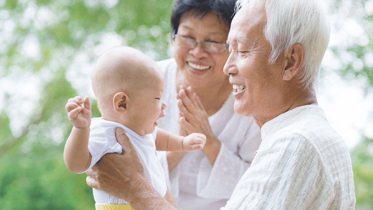 παππούδες κρατάνε το εγγόνι τους και χαμογελάνε