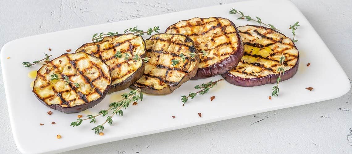 Charred slices of grilled eggplant on a plate Ψητή Μελιτζάνα με Σκόρδο & Φρέσκα Μυρωδικά