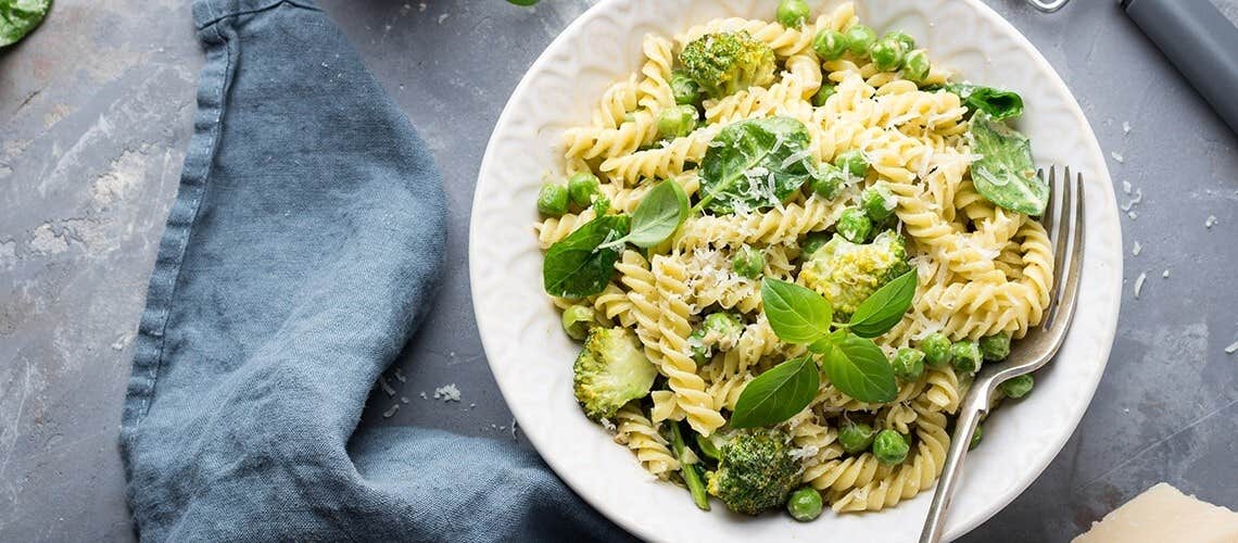 A bowl with spiral pasta with spinach and grated parmesan cheese Ζυμαρικά Ολικής με Σπανάκι & Παρμεζάνα