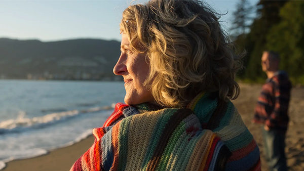 Μια γυναίκα στη παραλία τυλιγμένη σε μια κουβέρτα αγναντεύει τη θάλασσα