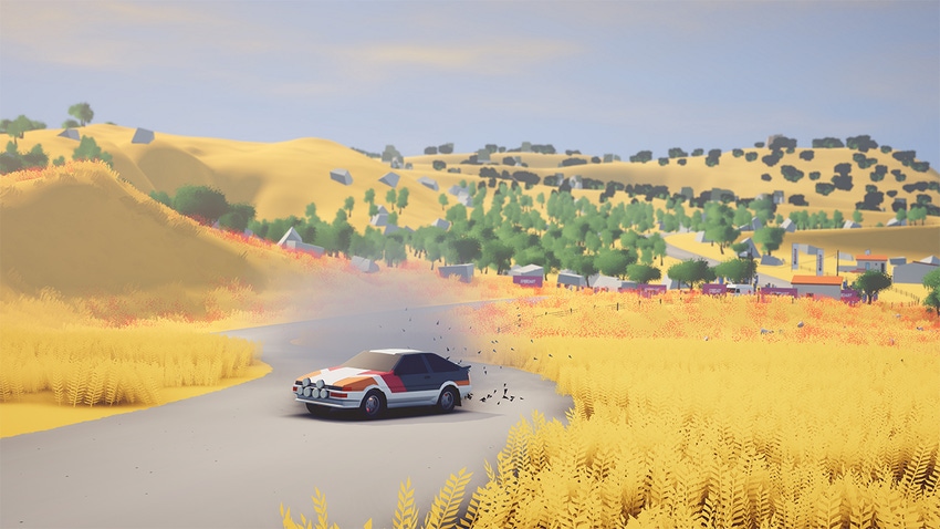 A rally car drifting down a road framed by golden fields