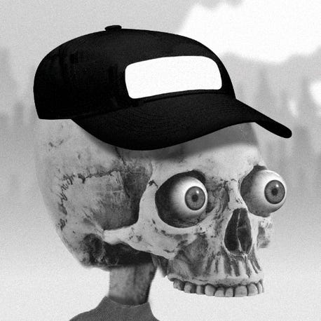 A terrifying mockup of a human skull with no lower jaw and round eyeballs in its eye sockets wearing a black baseball cap.