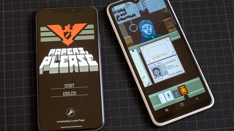 A photograph of Papers, Please playing on an iPhone and Android mobile phone.