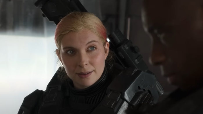 Spartan Kai 1-25, a blonde-haired woman in power armor, looks at another Spartan in the foreground. Spartan Kai 1-25, a blonde-haired woman in power armor, looks at another Spartan in the foreground.