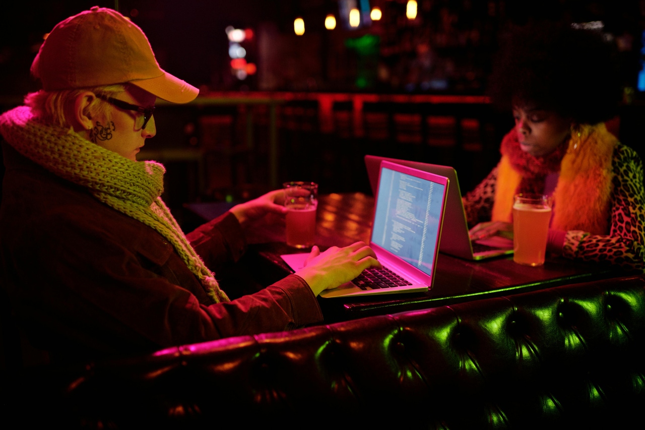 Two people coding on their laptops in a booth Two people coding on their laptops in a booth