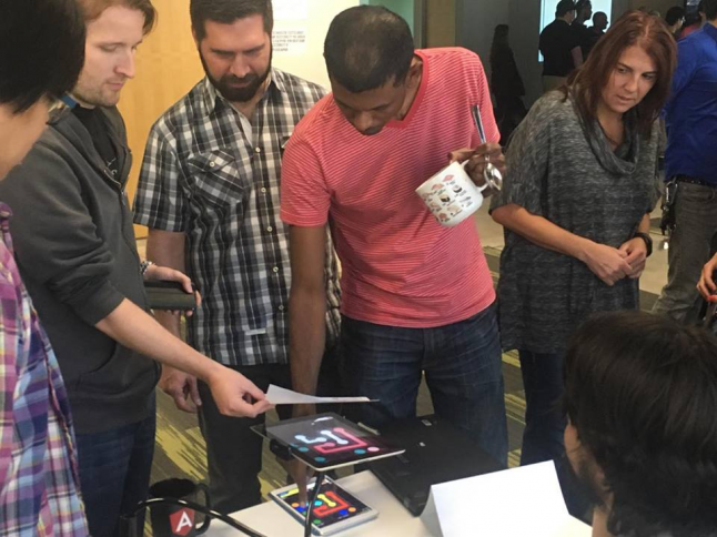 Crowd of developers looking at an ipad game with simulated colourblindness