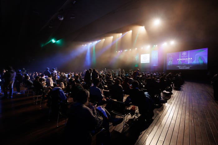 An Epiphany Dawn XM Anomaly event in December 2022 in Yokohama, Japan shows a large crowd in a dark, dynamically lit room.