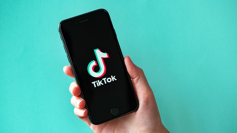 A person holding a phone with the TikTok logo on it.