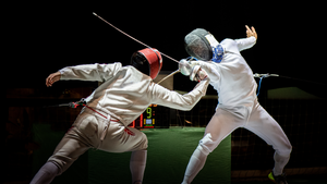 Two fencers cross blades in a competition. Two fencers cross blades in a competition.