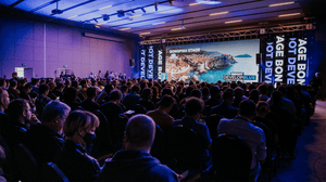 A photograph from a presentation at Reboot Develop showing a packed out room and a person on a stage A photograph from a presentation at Reboot Develop showing a packed out room and a person on a stage