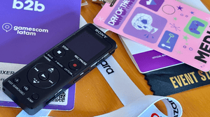A recording device placed on a table next to multiple press badges from game industry events A recording device placed on a table next to multiple press badges from game industry events