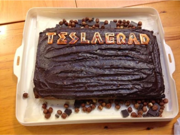 A picture of a cake with dark chocolate frosting, with the name Teslagrad written in icing.