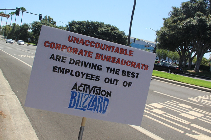 A sign reads "Unaccountable Corporate Bureaucrats are driving employees out of Activision Blizzard." A sign reads "Unaccountable Corporate Bureaucrats are driving employees out of Activision Blizzard."