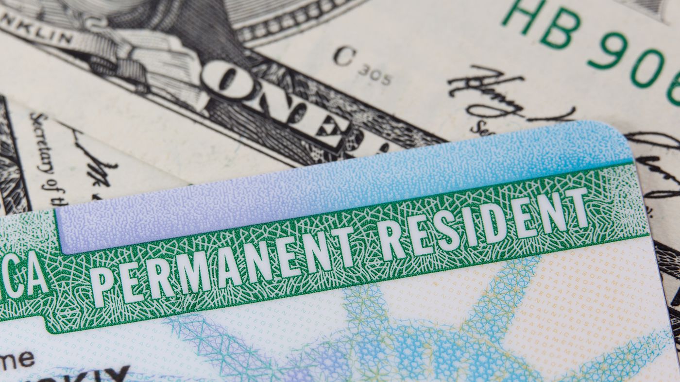 A photograph of a US Passport, social security card, and green card against an American flag. A photograph of a US Passport, social security card, and green card against an American flag.