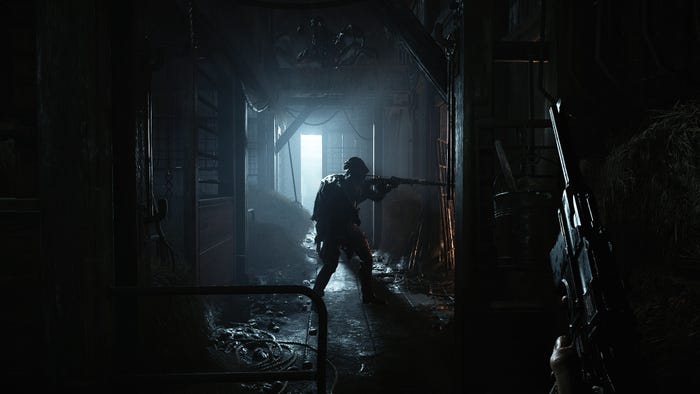 A player watches another player stalk through a dark hallway.