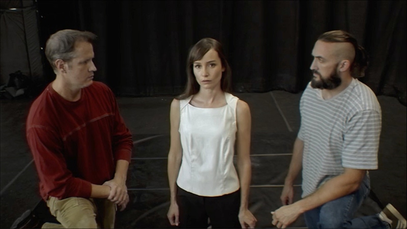 A screenshot from Immortality. Two men look at a woman who is looking at the camera.
